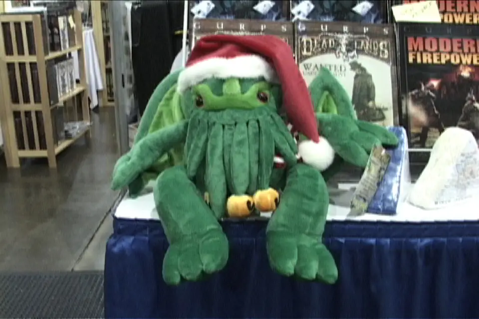 A plush Cthulhu in a Santa hat on a convention dealer table