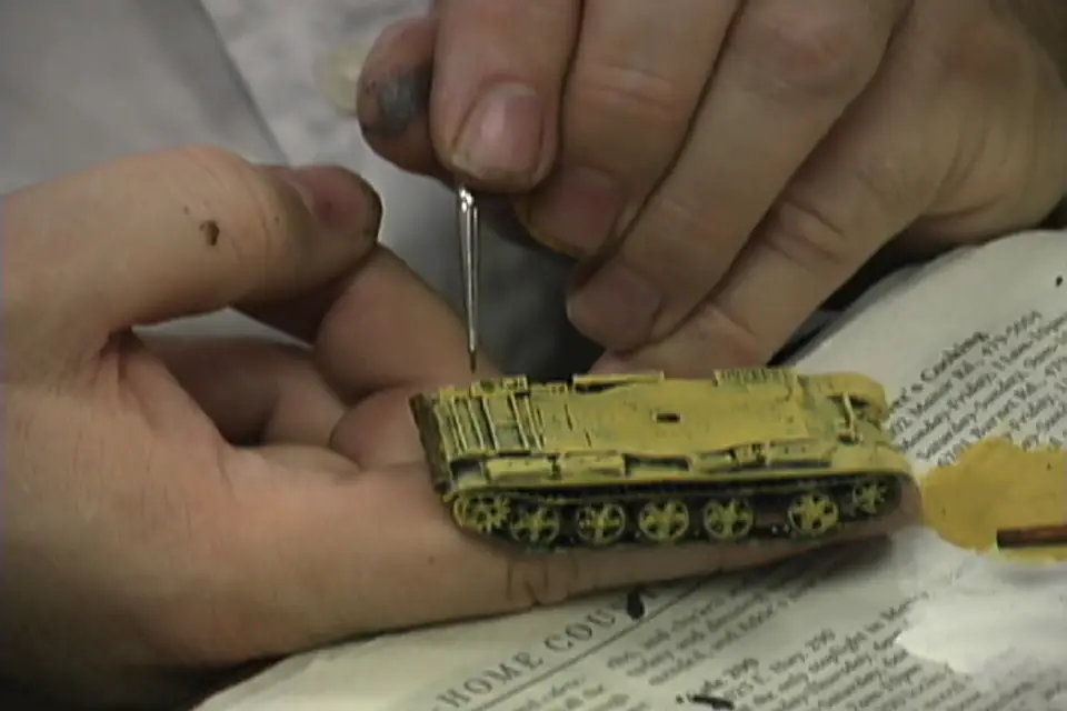 A hobbyist painting a miniature tank