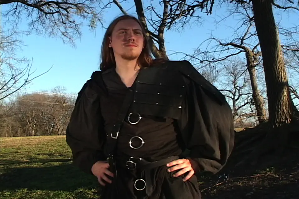 A costumed role-player in black leather under the trees